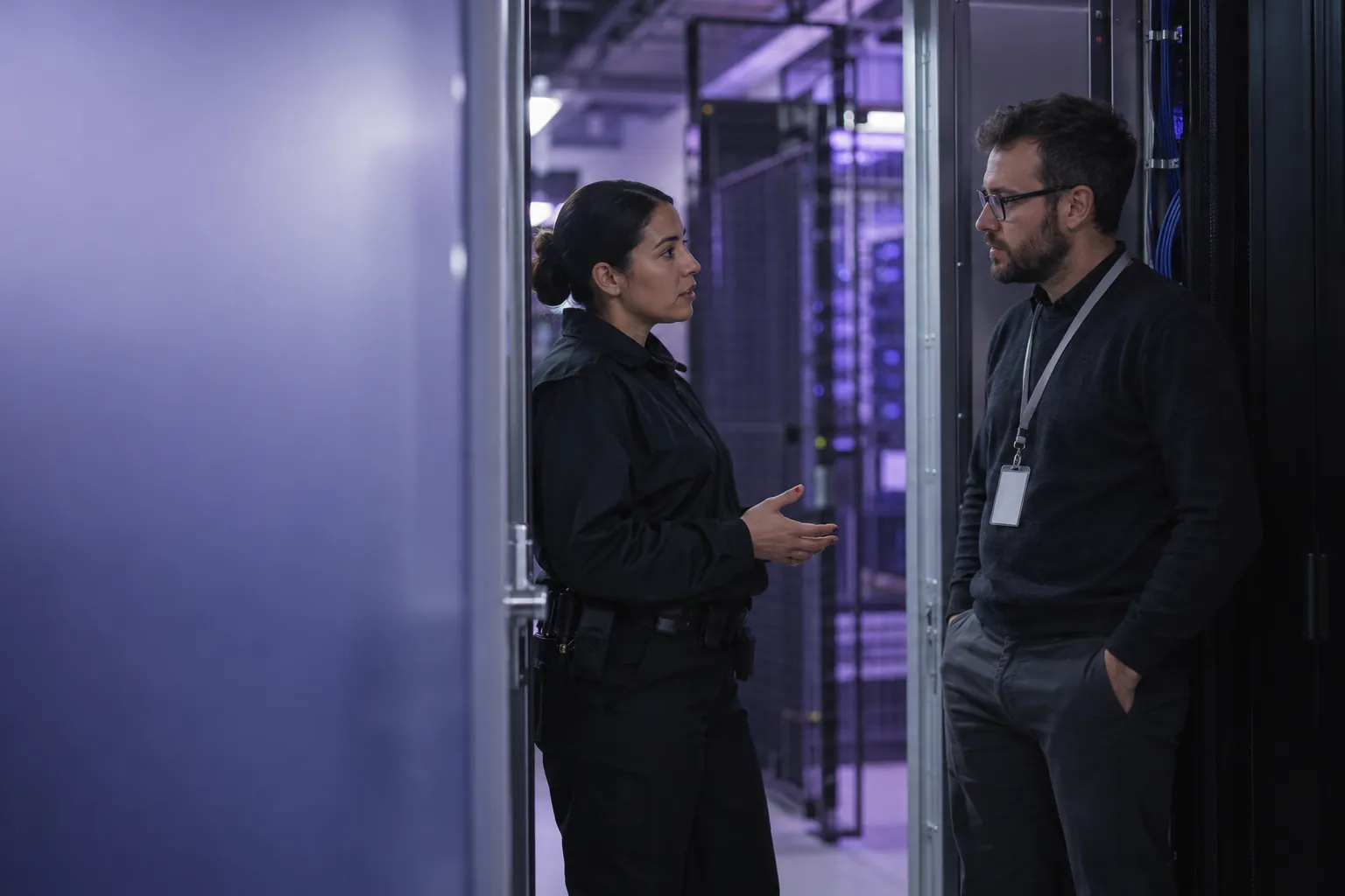 A security officer and an IT engineer talking at the doorway of a restricted-access server room