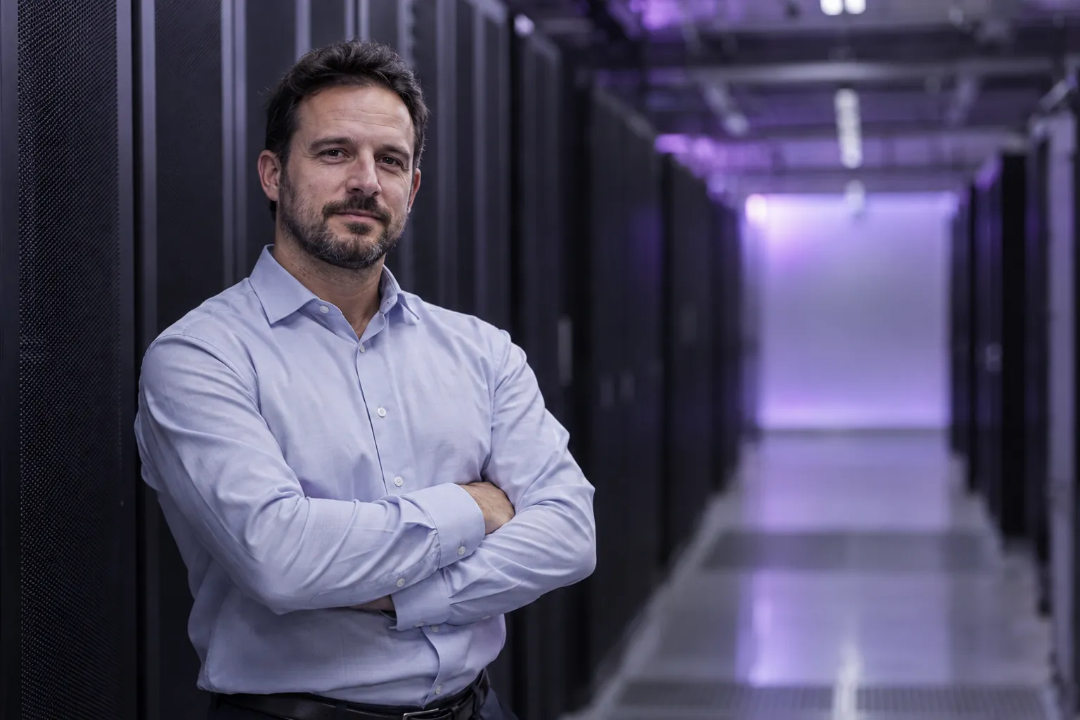 An IT manager standing in a data-centre corridor between server racks